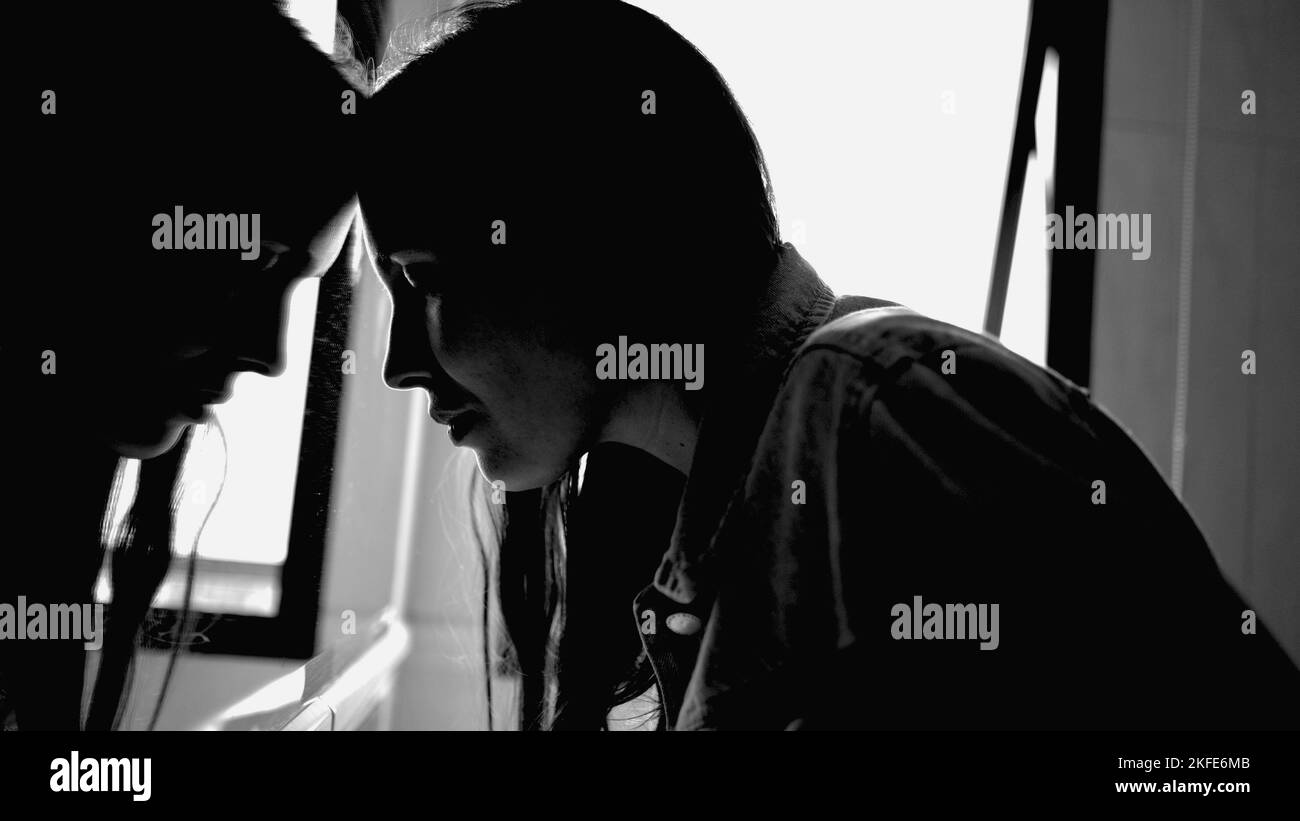 Depressed woman leaning on bathroom mirror reflection feeling sad and in distress. Monochromatic