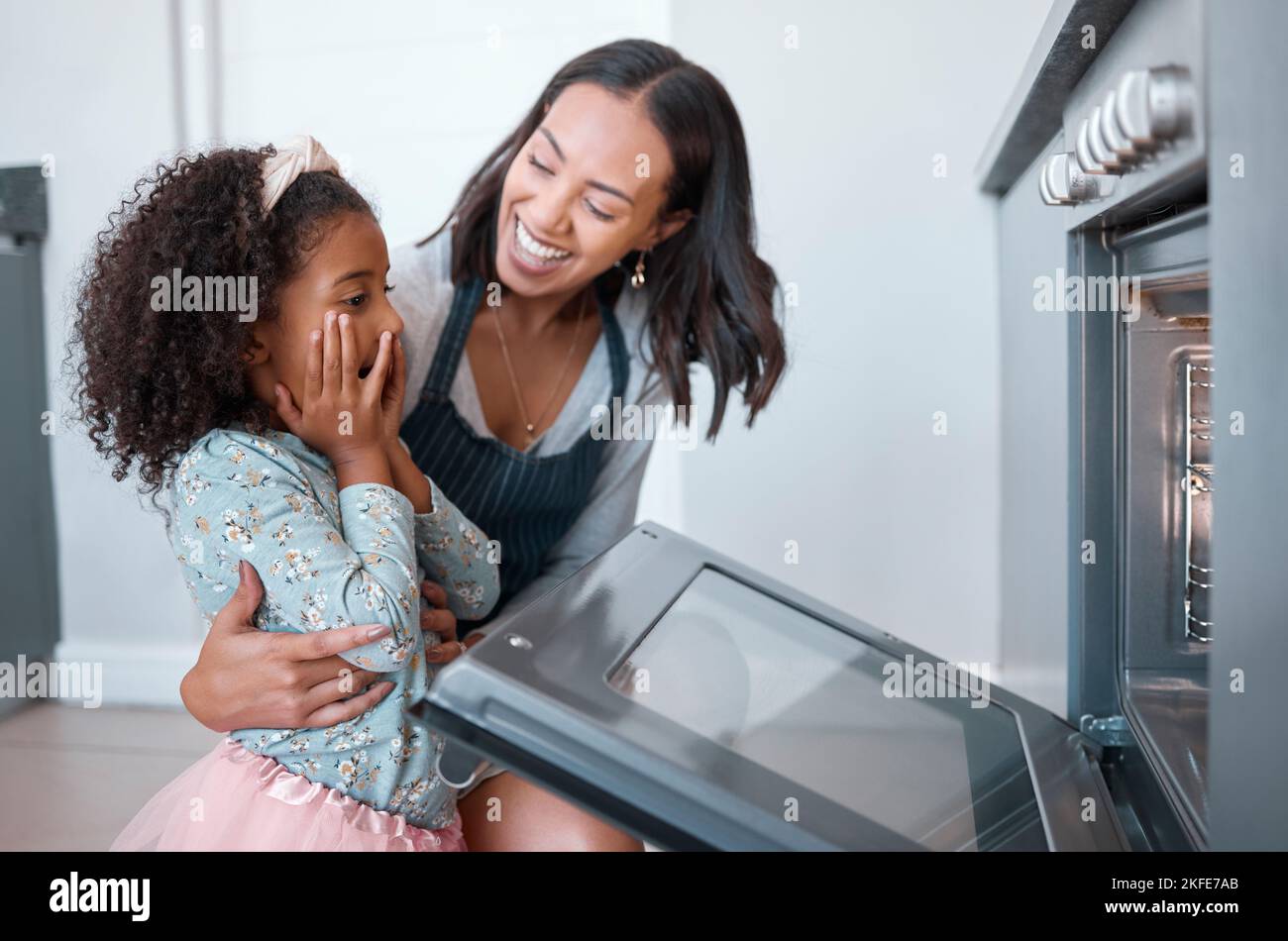 Woman, child and baking at the oven while waiting with surprise for food or baked food. Mother, daughter and kid using a convection stove or oven for Stock Photo