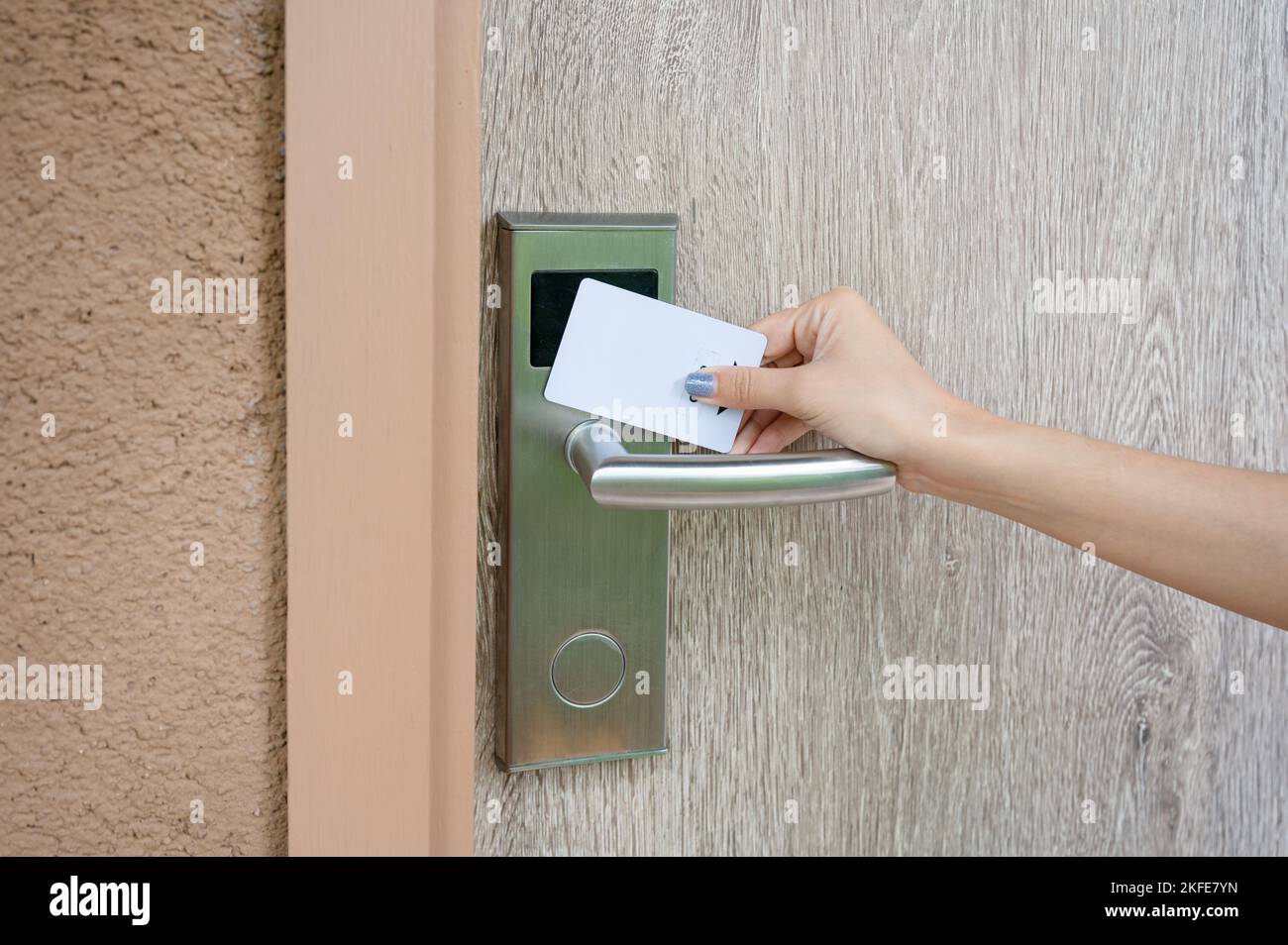 Hand holding key card scanning to unlock wooden door at resort. Digital door scanner access control security system Stock Photo