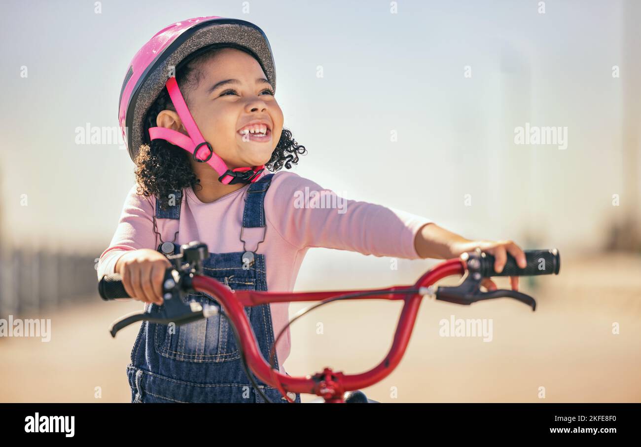 Thinking, eco friendly and girl cycling on a bike, learning and training in city with a smile. Playing, exercise and child on a bicycle for carbon Stock Photo