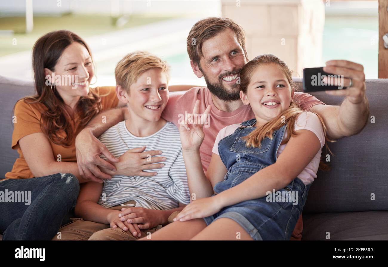 Phone, selfie and happy family on a sofa in the living room relaxing together at their modern house. Happiness, smile and parents taking a picture Stock Photo