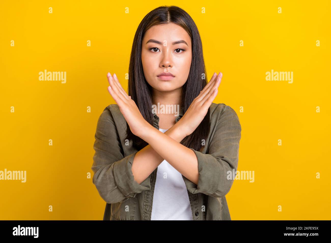 Portrait of serious gorgeous woman with long hairdo wear khaki shirt showings no stop gesture deny isolated on yellow color background Stock Photo