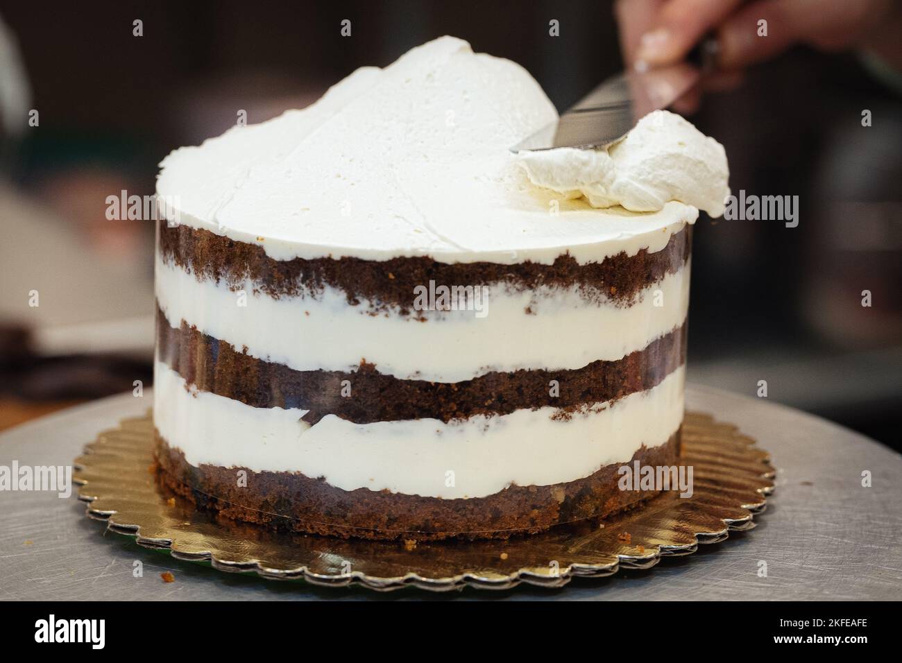 Putting the final frosting on a layer cake in a bakery Stock Photo