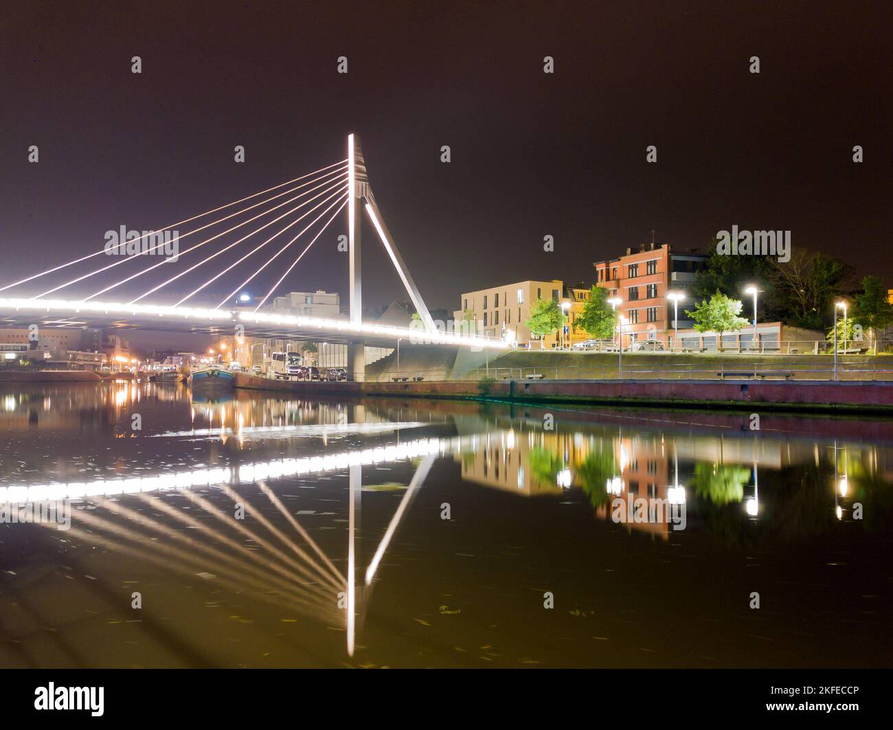 cityscape with modern concrette illumanite bridge at night and boats and cars in the background Stock Photo
