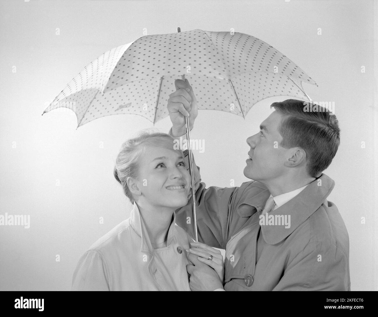 1960s couple. A happy smiling couple is standing under an umbrella. Sweden 1960 Conard ref 4254 Stock Photo