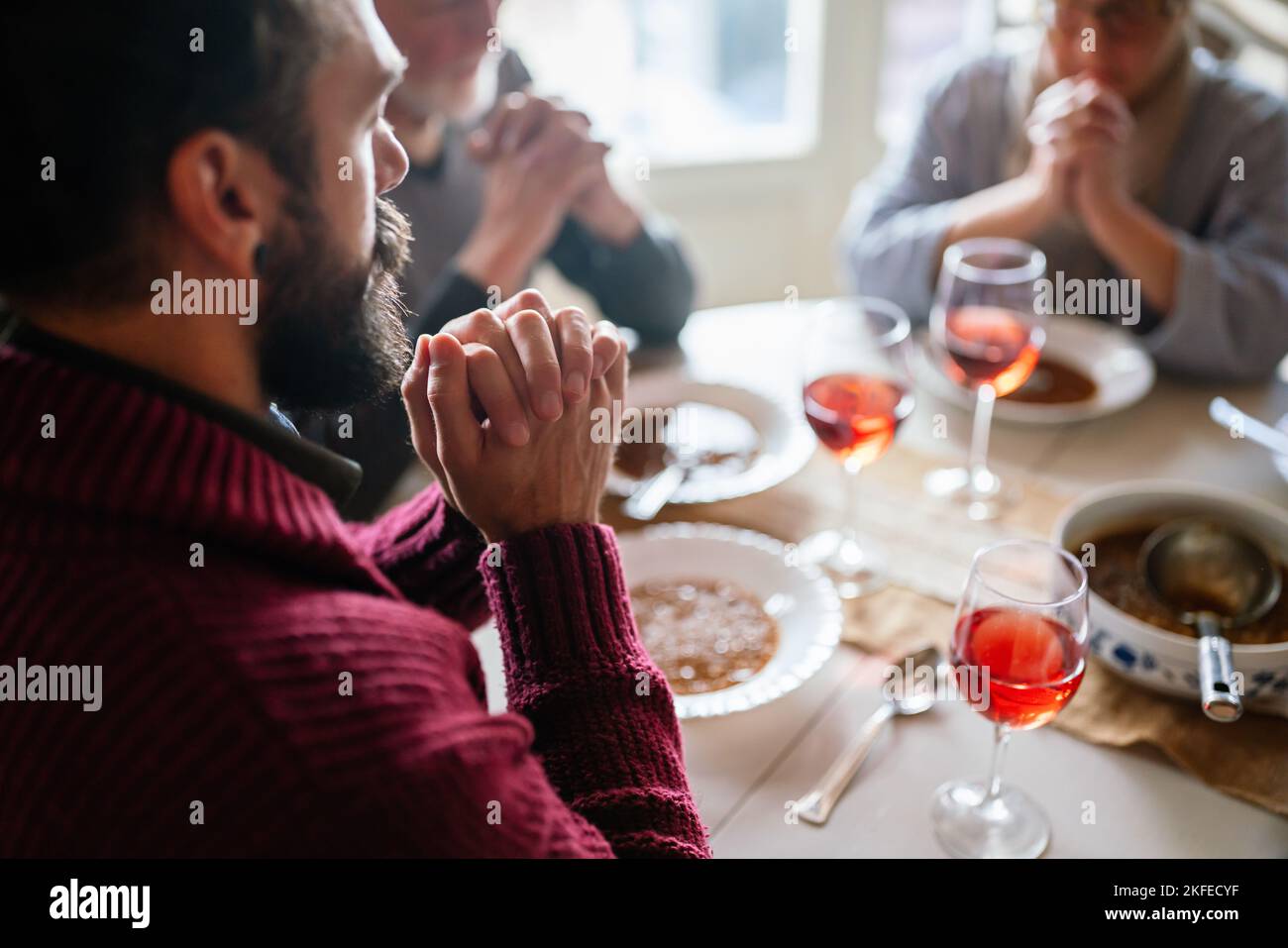 Family and religious concept. Group of multiethnic people with food praying before meal Stock Photo