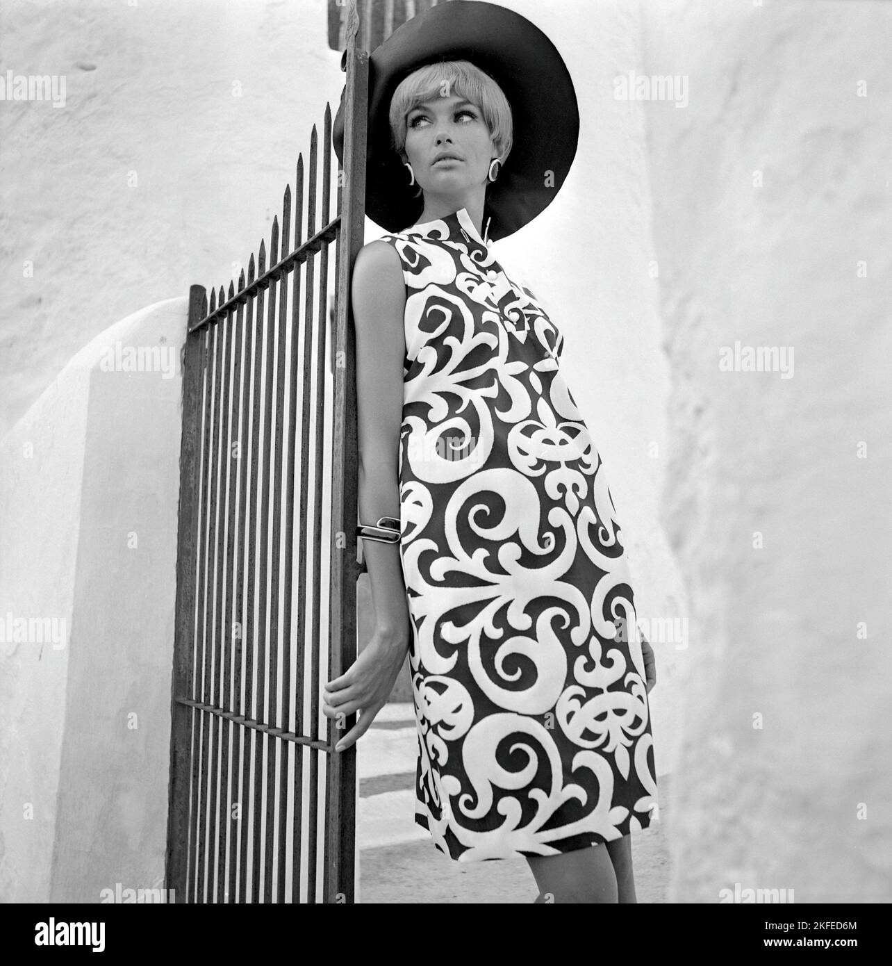 Fashion shoot on the spanish island Ibiza in the 1960s. A fashion model on location models the typical summer dress and hat. 1967 Stock Photo