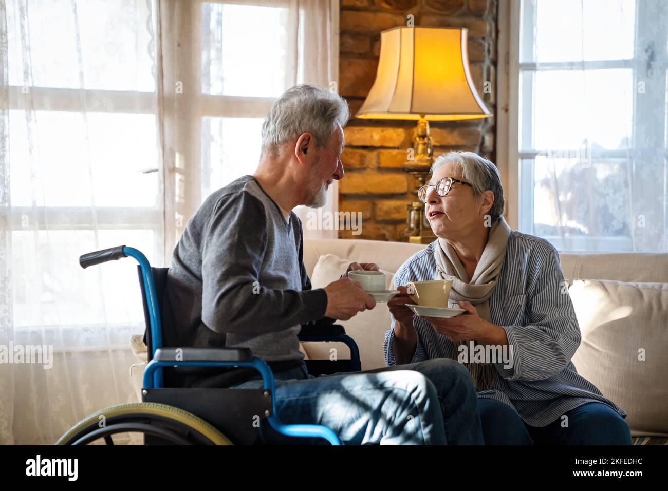 Mature man with disability in wheelchair having fun with wife. Family senior couple love concept Stock Photo