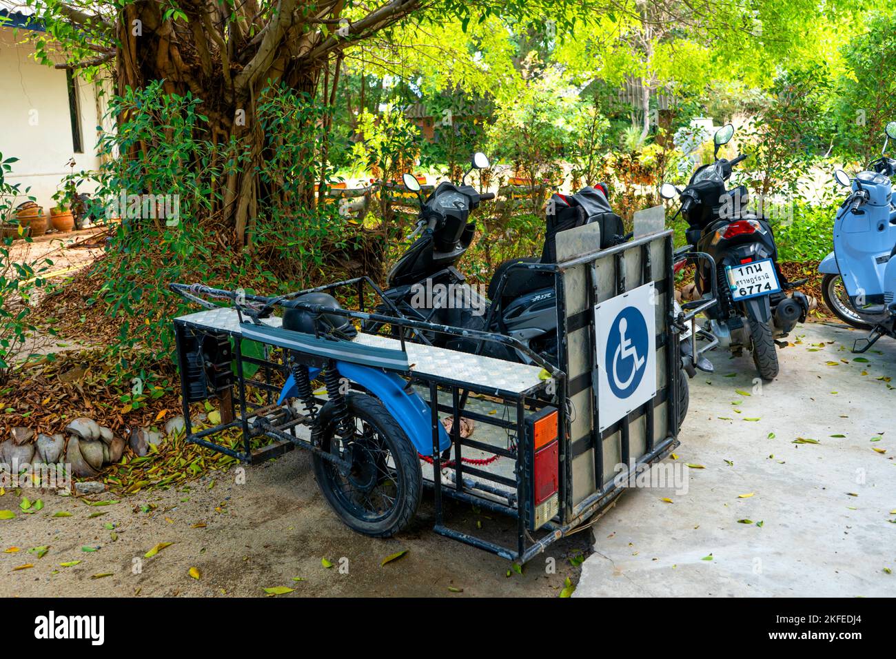 Scooter with a wheelchair trailer. Special adaptation of bikes in Asia. Samui, Thailand - 02.13.2020 Stock Photo