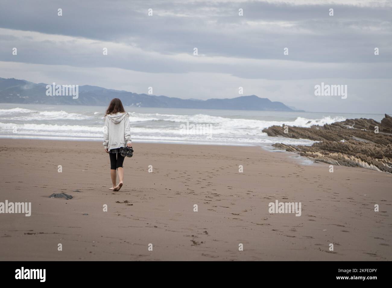 Girl walks on the Itzurun Beach in Zumaia, Basque Country, Spain. Stock Photo