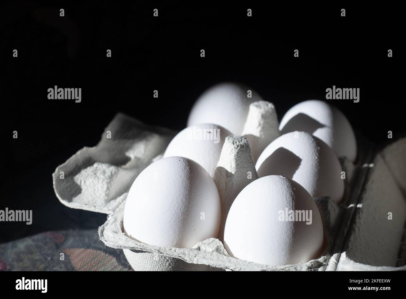 Six white fresh eggs in grey paper container. High contrast picture