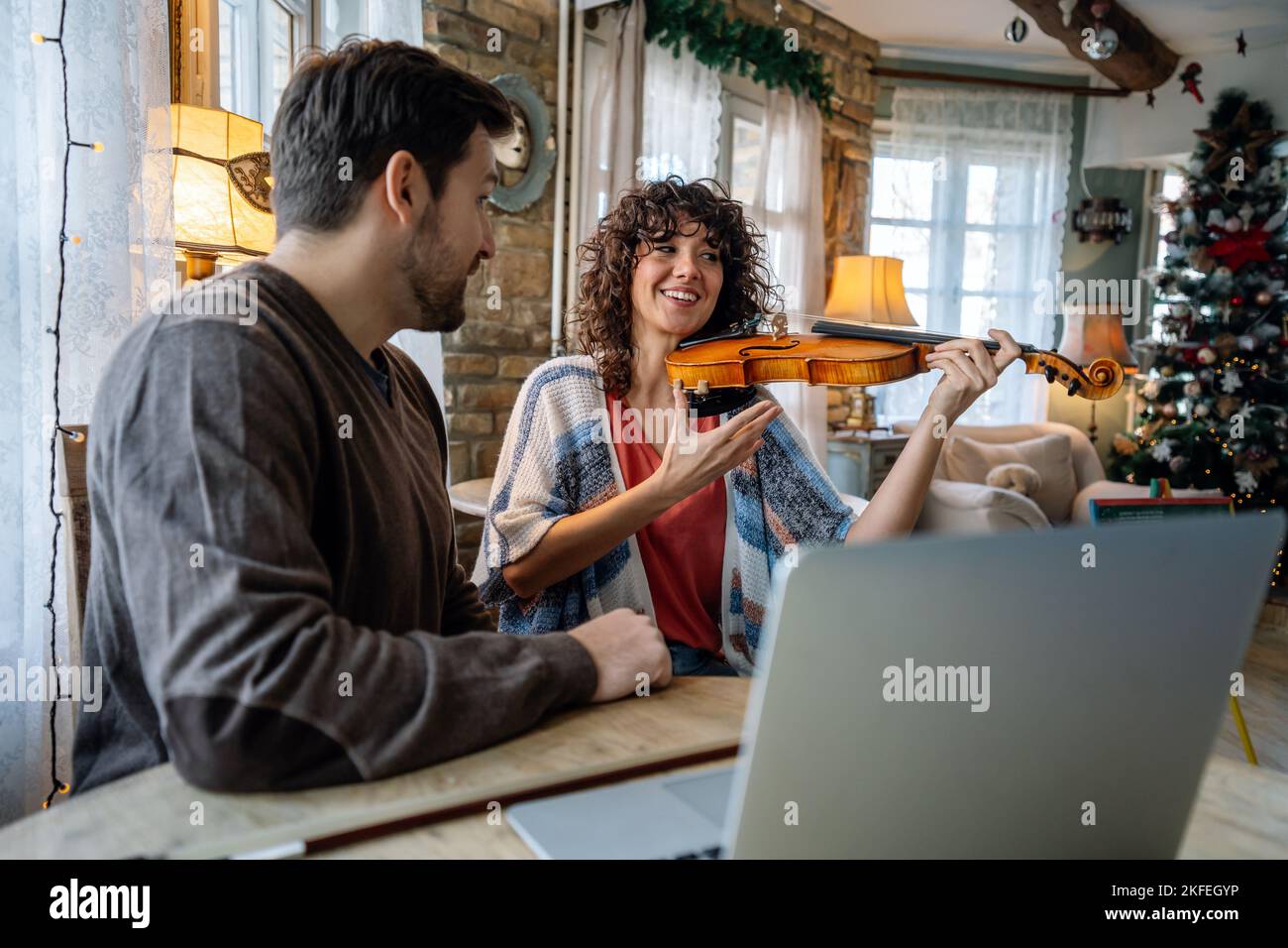 Violin teacher helping a woman student at home Stock Photo