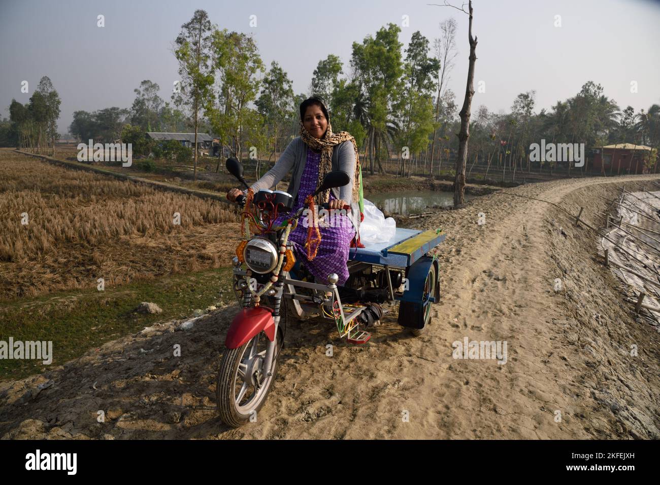 Woman riding electric tricycle, Pakhiralay, Gosaba, Sunderban, South 24 Pargana, West Bengal, India Stock Photo
