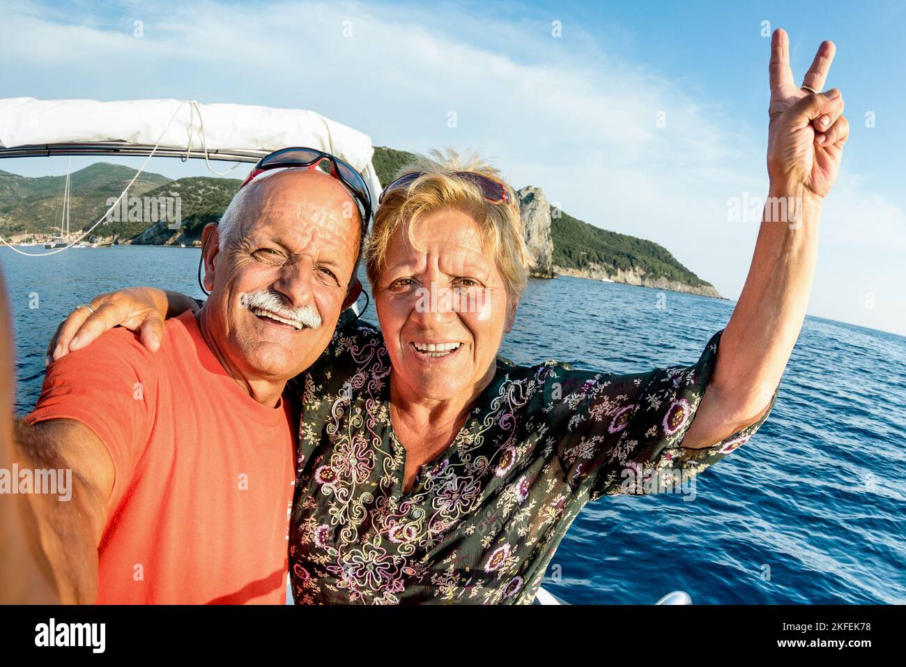 Adventurous senior couple taking selfie at Giglio Island on luxury speedboat - Active elderly travel lifestyle concept on happy tour moment - Retired Stock Photo