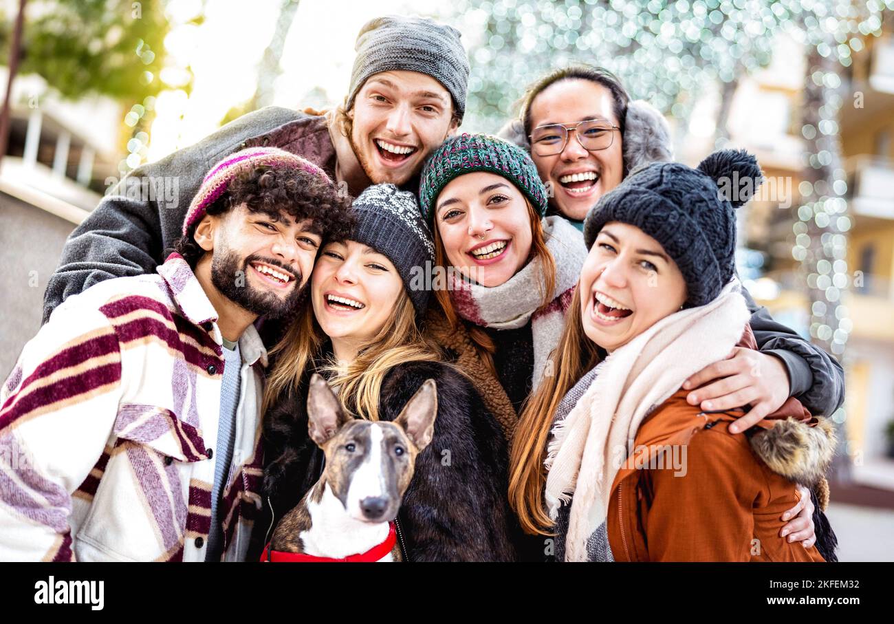 Happy multicultural guys and girls taking selfie on warm fashion clothes - Trendy life style concept with millenial friends group having fun together Stock Photo