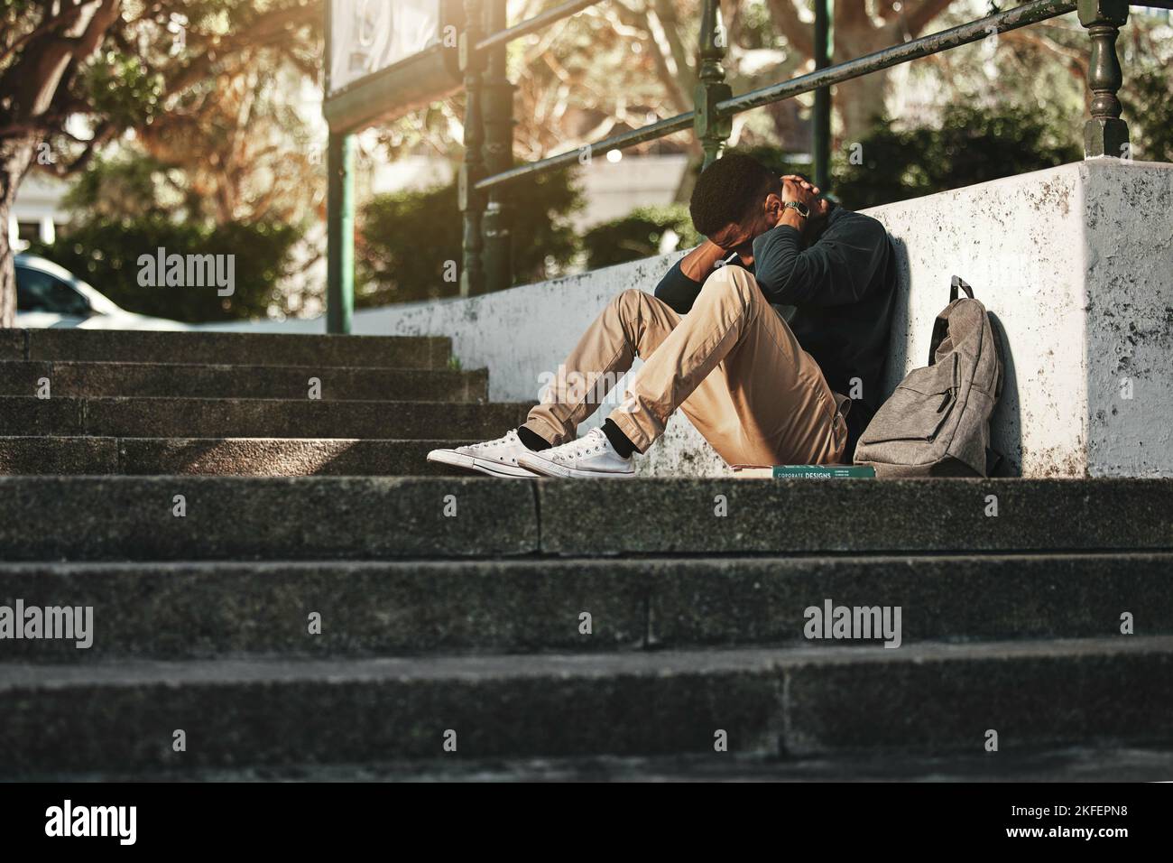 Sad, depression and black man with anxiety at college, stress and headache from education on the stairs at campus. Depressed, frustrated and student Stock Photo