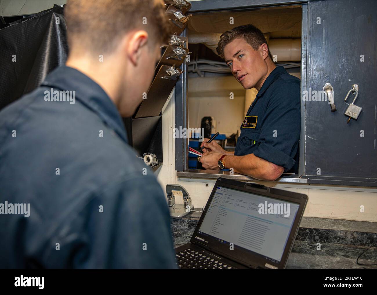 PHILIPPINE SEA (Sept. 13, 2022) Personnel Specialist Seaman Cameron Stine, left, from Ft. Worth, Texas, and Lt. j.g. James Lendon, from Delmar, New York, conduct administrative work aboard Ticonderoga-class guided-missile cruiser USS Chancellorsville (CG 62) in the Philippine Sea on Sept. 13, 2022. Chancellorsville is forward-deployed to the U.S. 7th Fleet in support of security and stability in the Indo-Pacific and is assigned to Commander, Task Force 70, a combat-ready force that protects and defends the collective maritime interest of its allies and partners in the region. Stock Photo