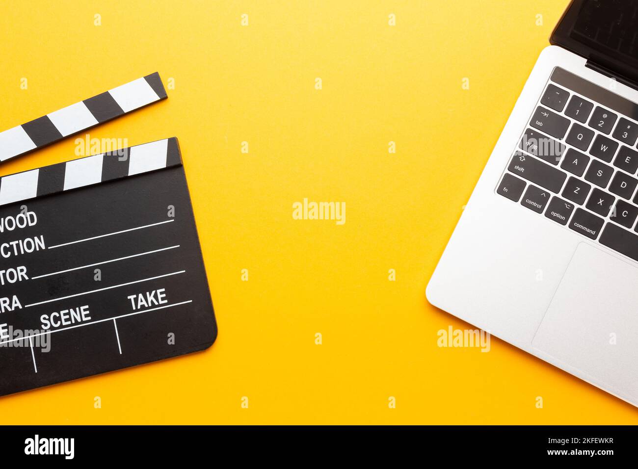 Office stuff with movie clapper, laptop, coffee cup, on yellow table - top view shot. High quality photo Stock Photo