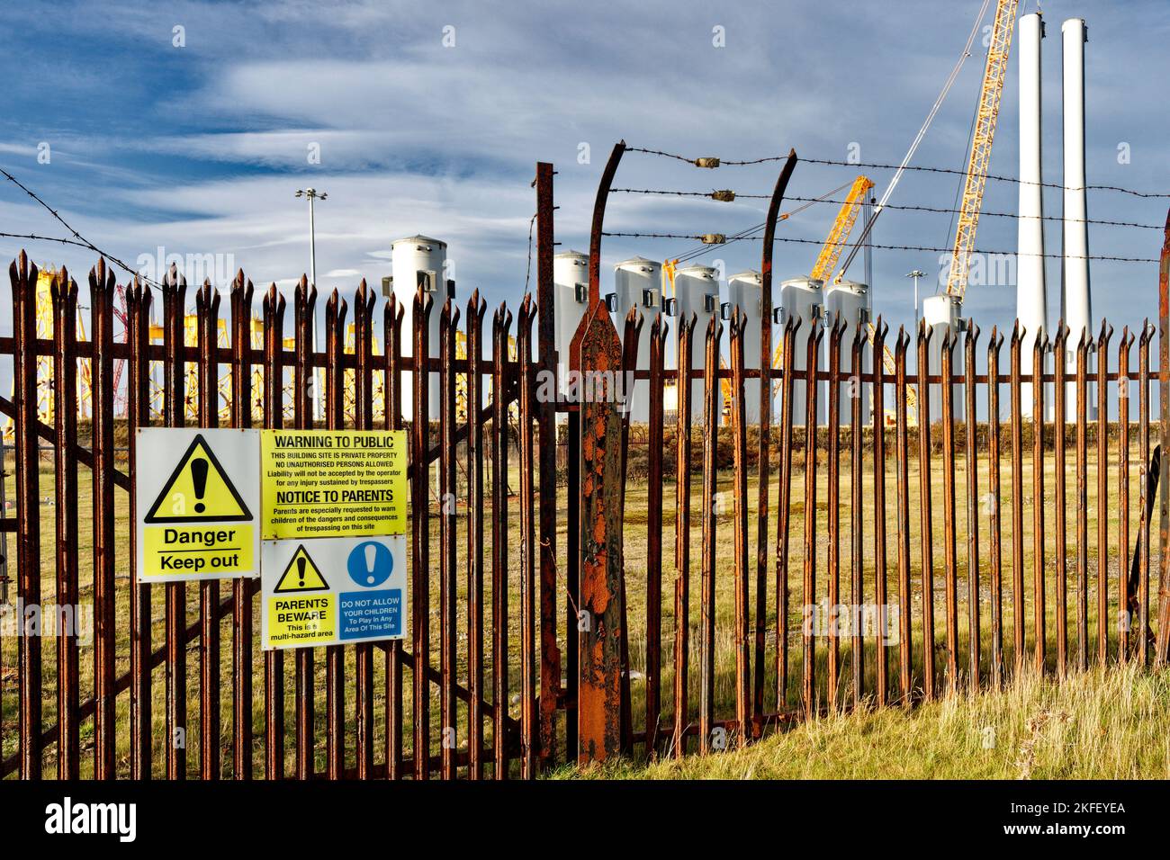 Cromarty Firth Nigg Scotland public and parent danger warning signs on wind turbine construction yard fence Stock Photo