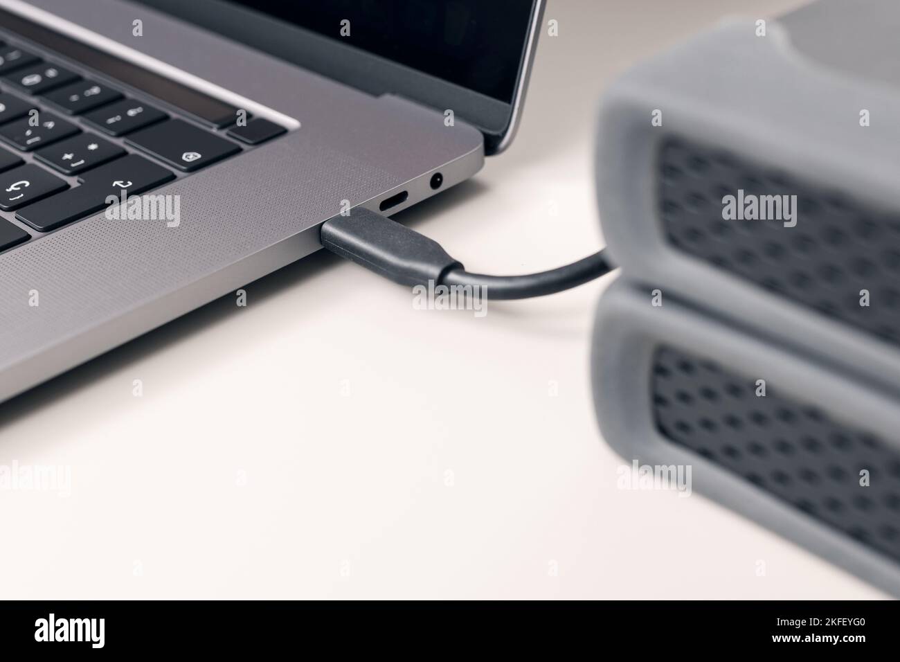 Detail of External hard disk cable connected to a modern laptop computer on desk Stock Photo