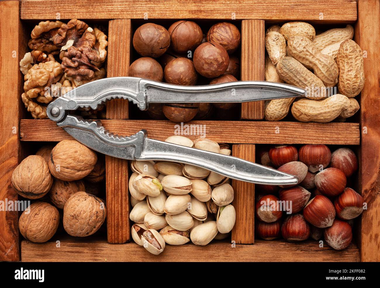 Different nuts in a wooden box and a nut cracker. Stock Photo
