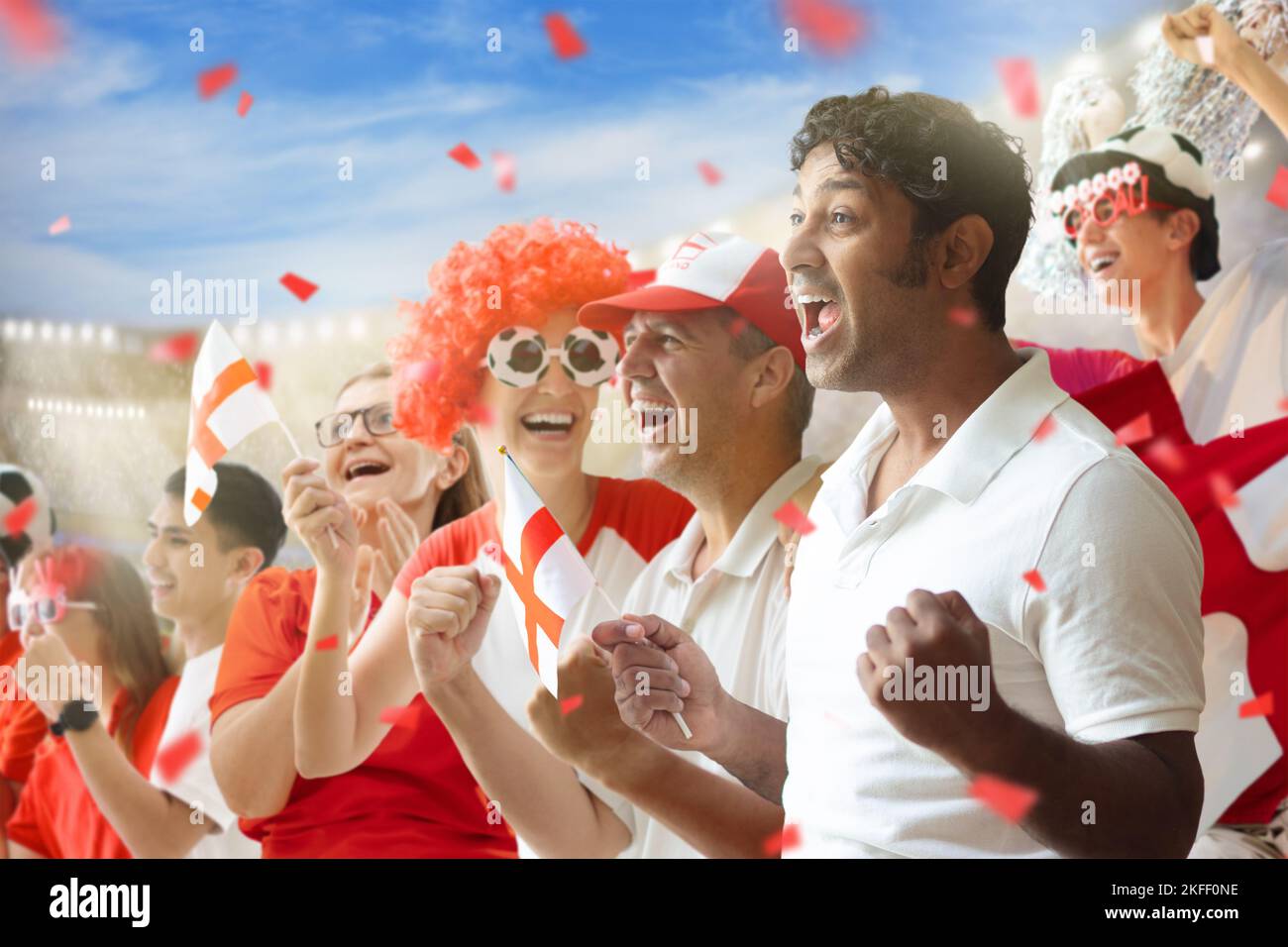 England football supporter on stadium. English fans on soccer pitch watching team play. Group of British chee Stock Photo