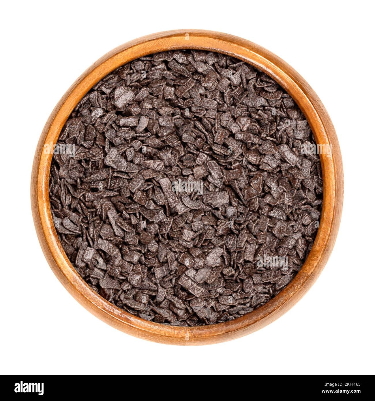Dark chocolate flakes topping, in a wooden bowl. Chocolate sprinkles, used in baking as decoration or to add texture to cookies, cakes and desserts. Stock Photo