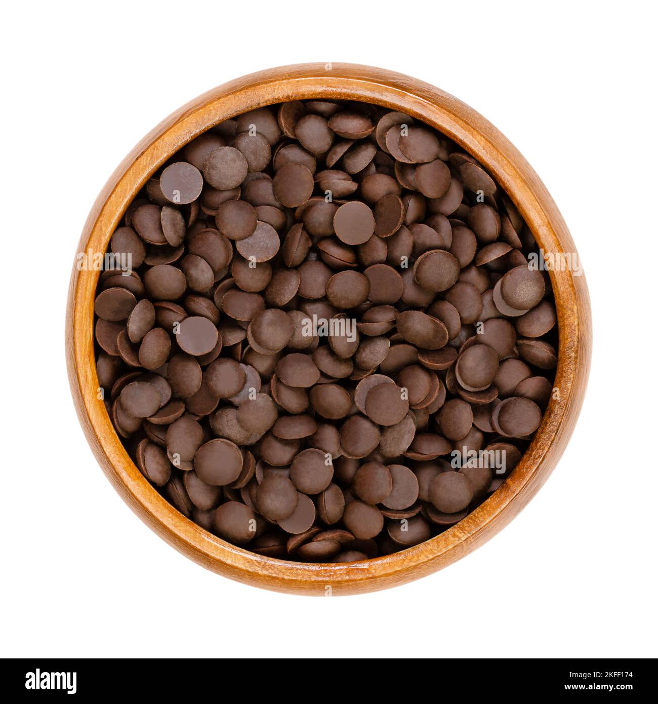 Bittersweet chocolate drops, couverture in a wooden bowl. Chocolate coating mass in drop form. A topping and flavoring for cookies and desserts. Stock Photo