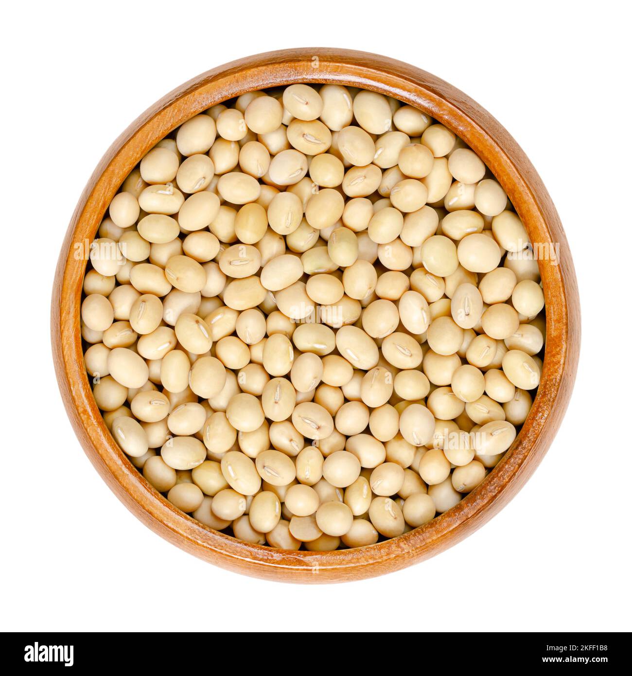 Raw soybeans, in a wooden bowl. Whole and dried seeds of the legume and oilseed Glycine max, also known as soy bean or soya bean. Stock Photo