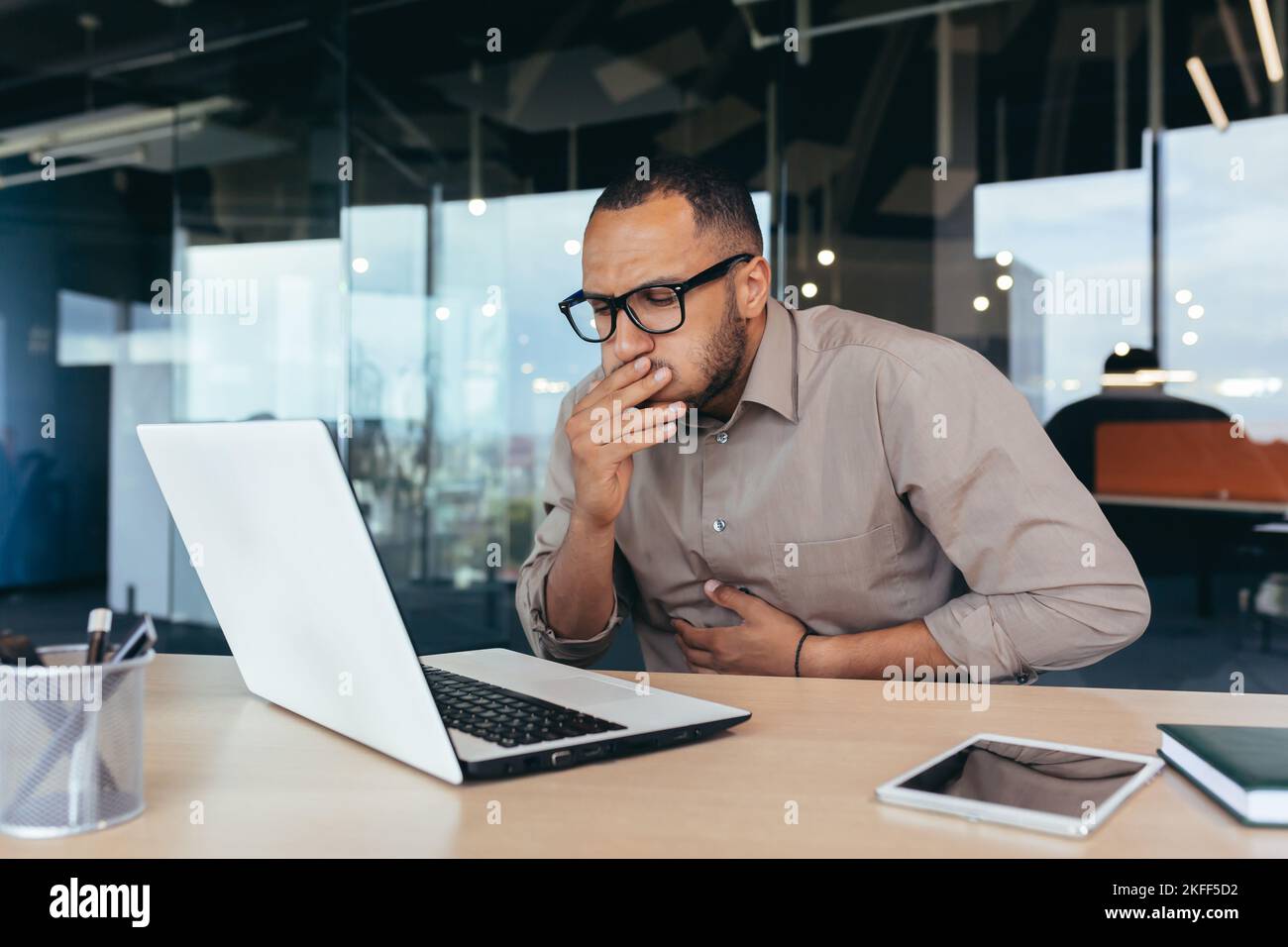 Nausea and stomach ache, sick african american businessman working inside office, man poisoned by bad food at lunch. Stock Photo