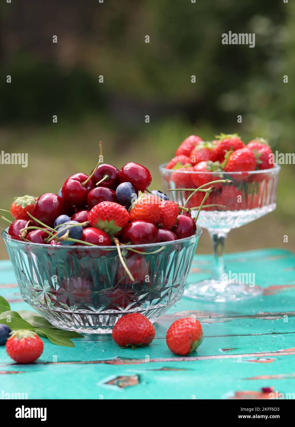 Glass bowl full of juicy organic berries. Summer still life with strawberry, sweet cherry, blueberry. Eating fresh concept. Stock Photo