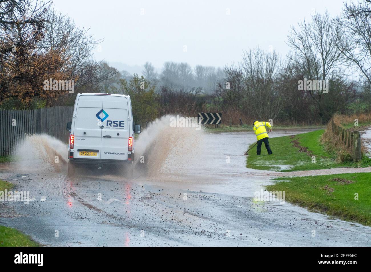 Angus, Scotland, United Kingdom 18th of November 2022. An amber warning for rain issued by the Met Office for the county Angus in Scotland. Pictured - good samaritan trying to unclog the drain, gets soaked by passing van driving on the Hillside to Stracathro road. Credit:Barry Nixon/Alamy Live News Stock Photo