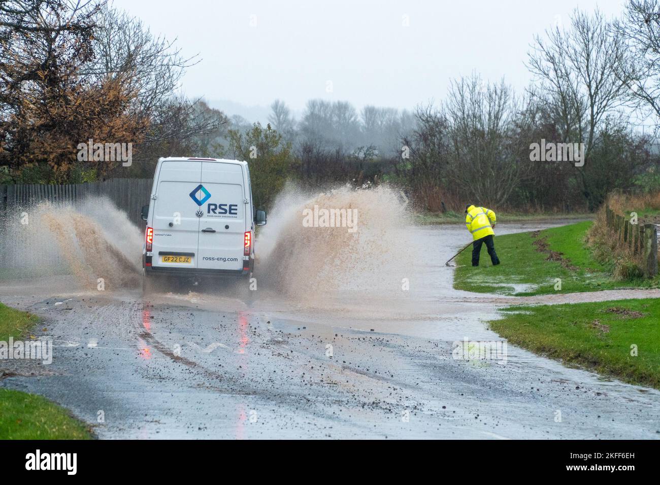 Angus, Scotland, United Kingdom 18th of November 2022. An amber warning for rain issued by the Met Office for the county Angus in Scotland. Pictured - good samaritan trying to unclog the drain, gets soaked by passing van driving on the Hillside to Stracathro road. Credit:Barry Nixon/Alamy Live News Stock Photo