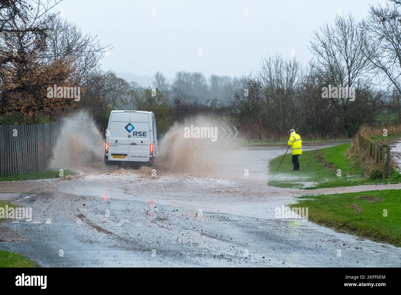 Angus, Scotland, United Kingdom 18th of November 2022. An amber warning for rain issued by the Met Office for the county Angus in Scotland. Pictured - good samaritan trying to unclog the drain, gets soaked by passing van driving on the Hillside to Stracathro road. Credit:Barry Nixon/Alamy Live News Stock Photo