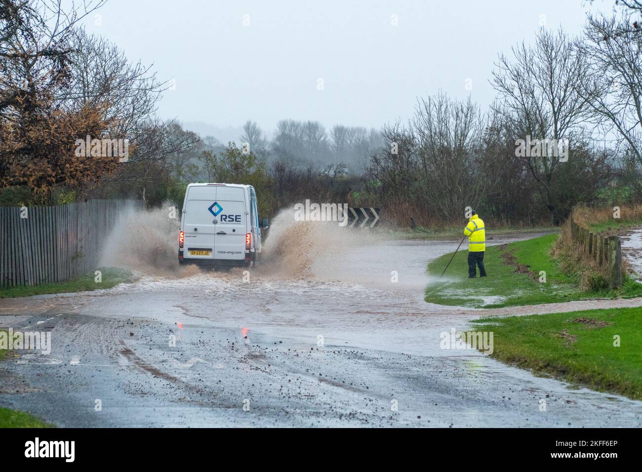 Angus, Scotland, United Kingdom 18th of November 2022. An amber warning for rain issued by the Met Office for the county Angus in Scotland. Pictured - good samaritan trying to unclog the drain, gets soaked by passing van driving on the Hillside to Stracathro road. Credit:Barry Nixon/Alamy Live News Stock Photo