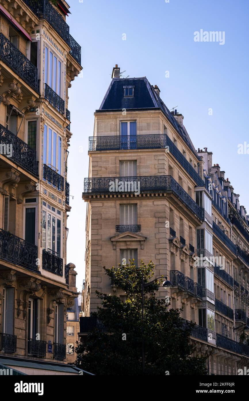 The vertical low-angle shot of modernized medieval buildings' exteriors before the blue skyline in Paris Stock Photo
