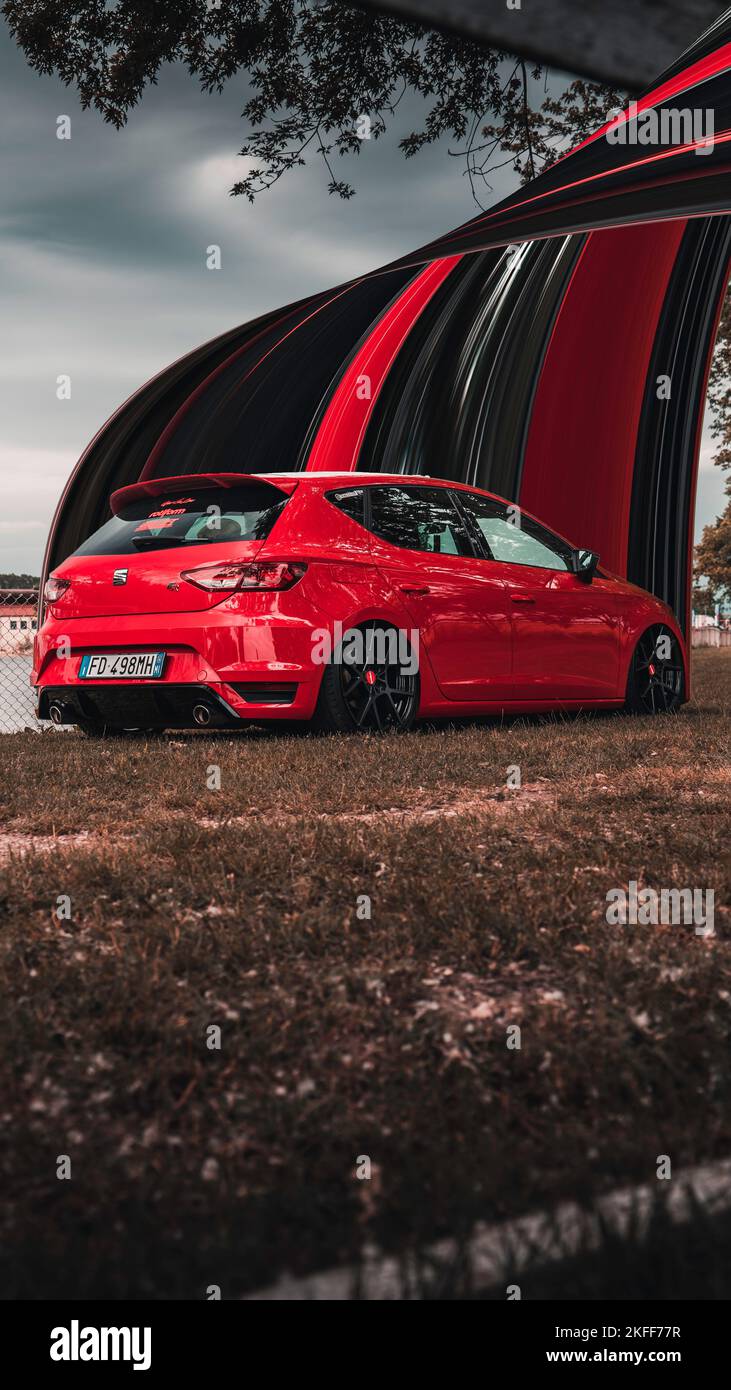 A vertical red SEAT Leon car on the lakeshore during an event Stock Photo