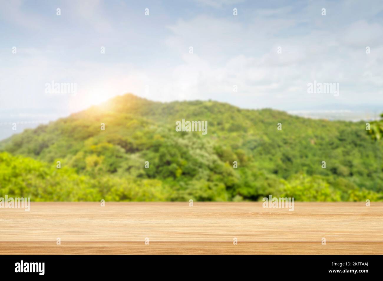 landscape with green hill, mountains, blue sky, sunrise and blank pine table, shelf for montage as display. Blurred nature background and board with p Stock Photo