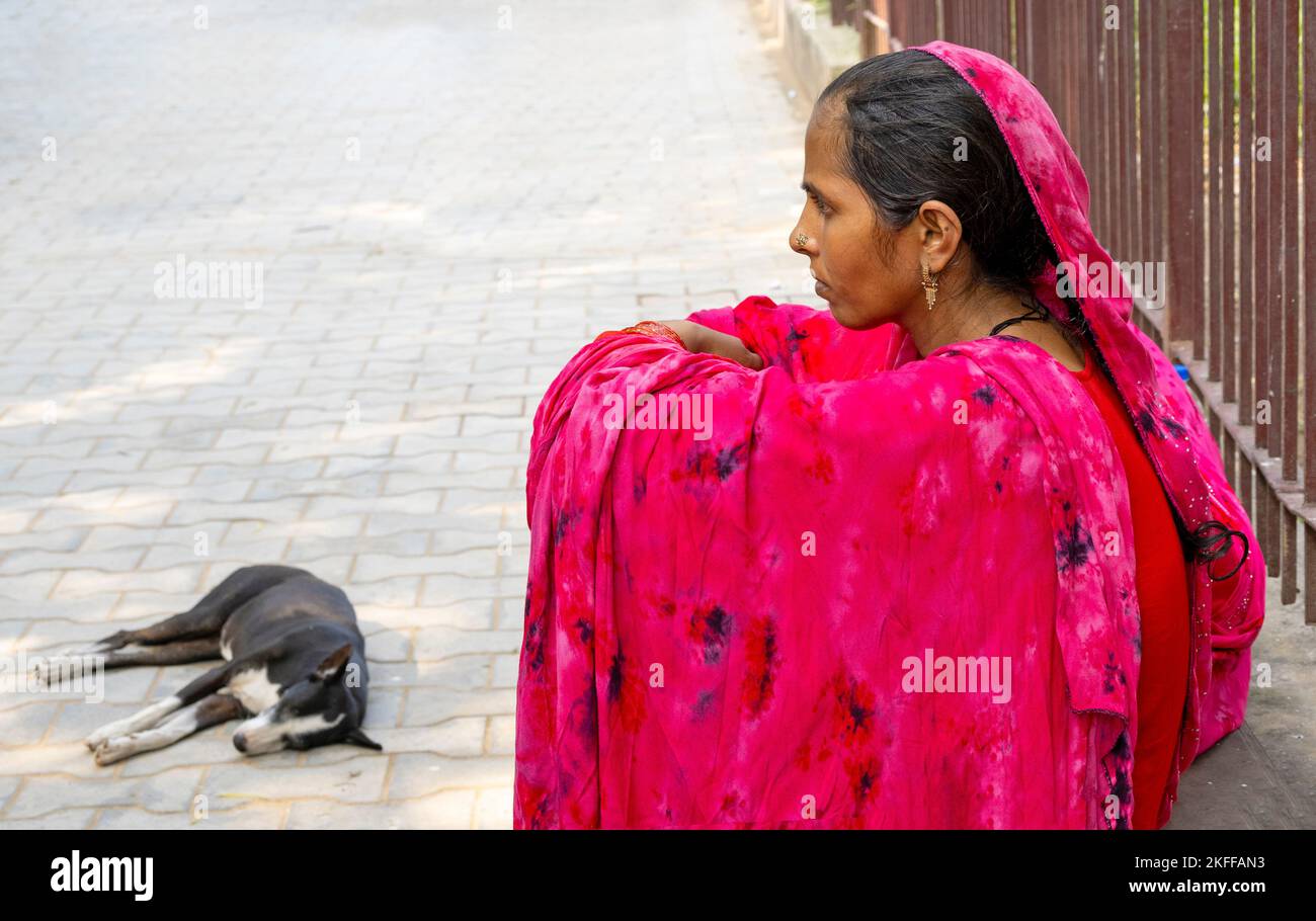 NEW DELHI - SEP 20: Unidentified indian woman sitting on the ground and dressed in traditional bright red dress in New Delhi on September 20. 2022 in Stock Photo