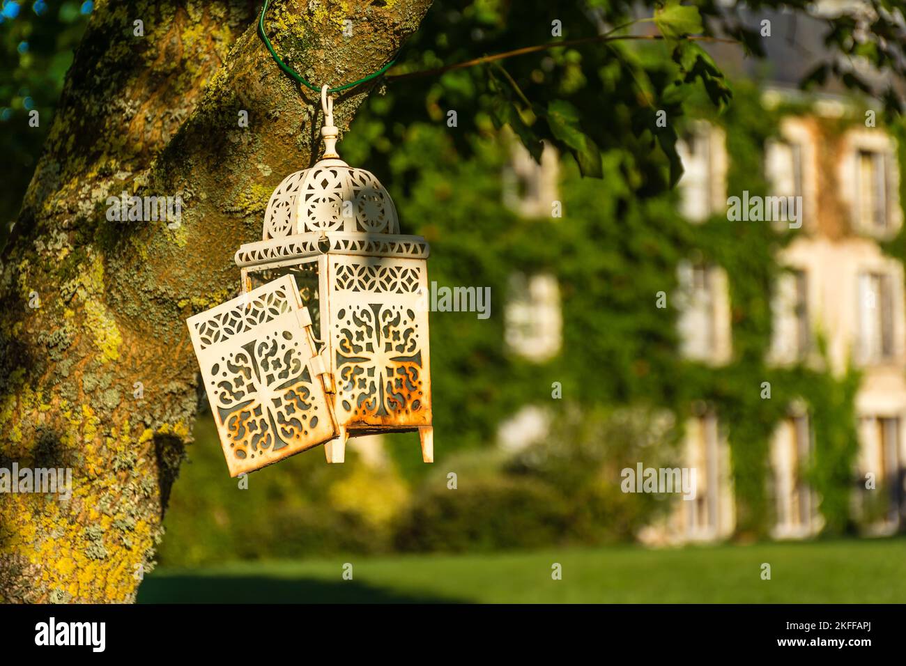 Scenic view of old rusty lantern hanging on tree with old building in background in Loire valley in France Stock Photo