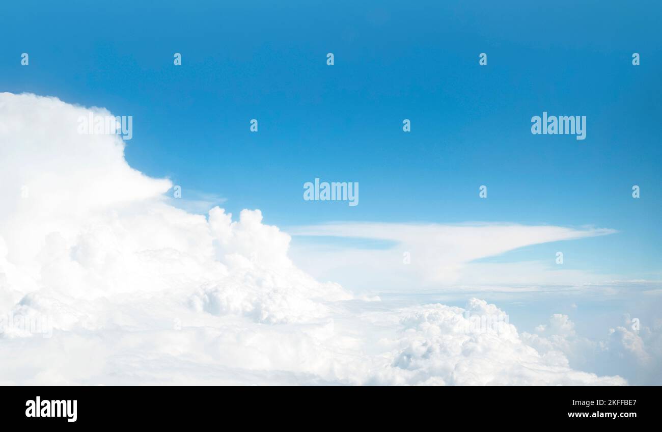 Panoramic view of blue sky and сumulus clouds through an airplane window. Flight above white cloud and horizon. Stock Photo