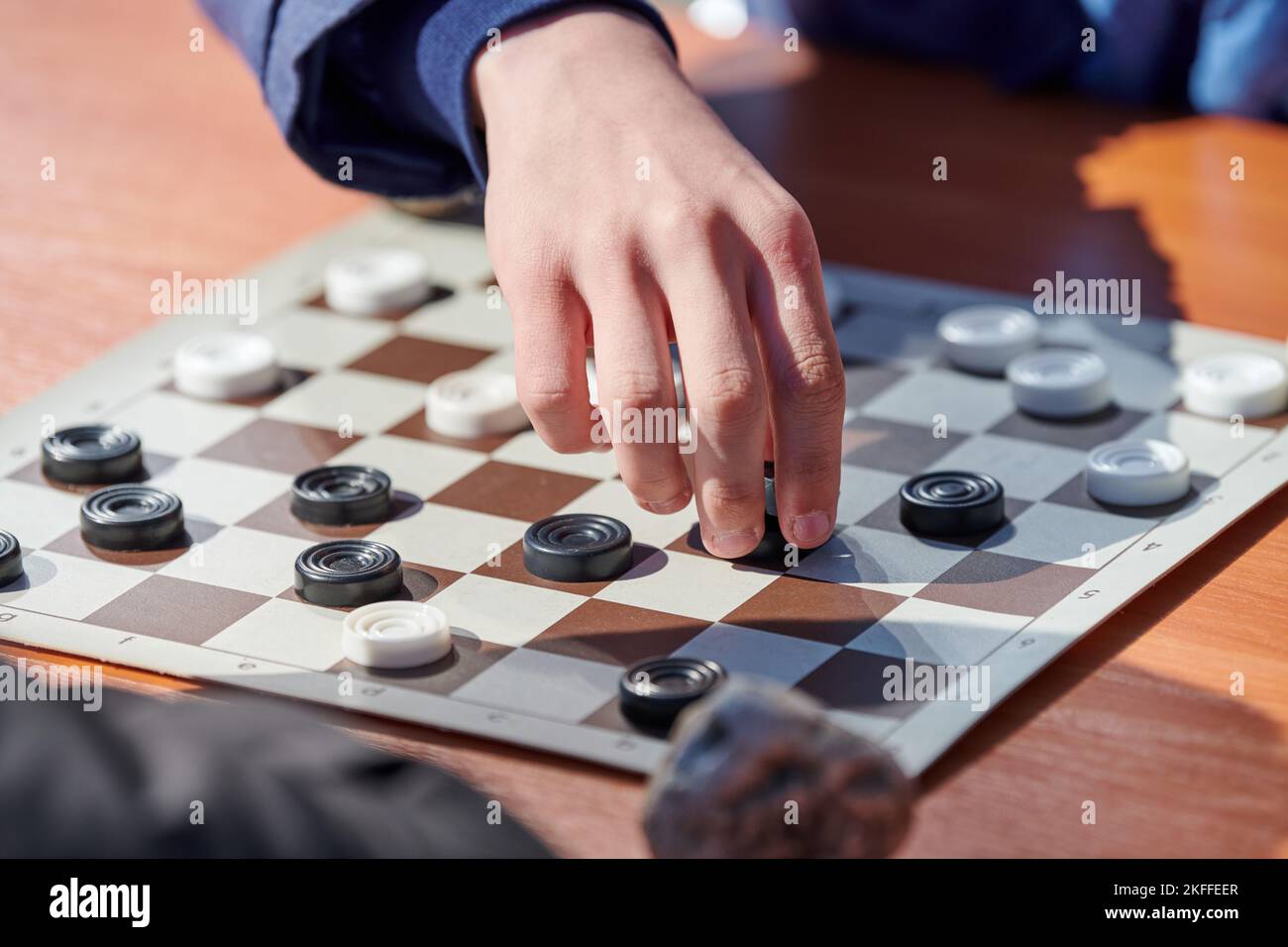Outdoor checkers tournament on paper checkerboard on table, close up