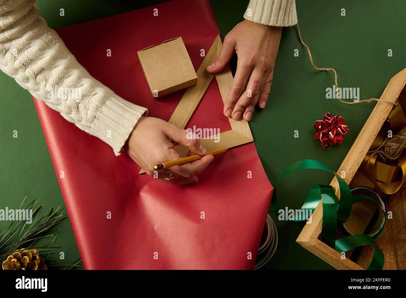 Female hands using a wooden pencil and triangular ruler draw on gift