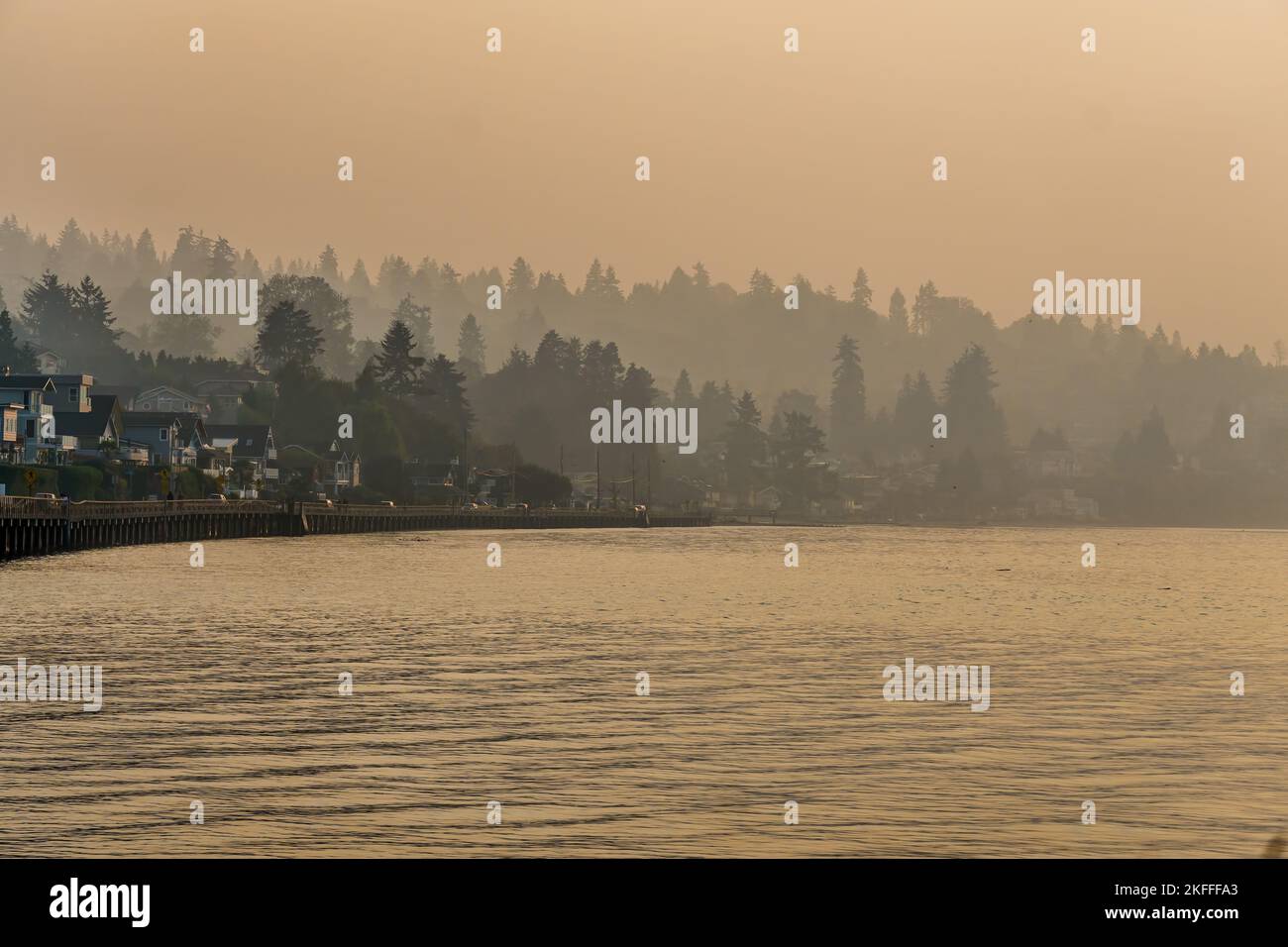 Smoke fills the air with waterfront homes and a boardwalk below in Redondo Beach, Washington. Stock Photo