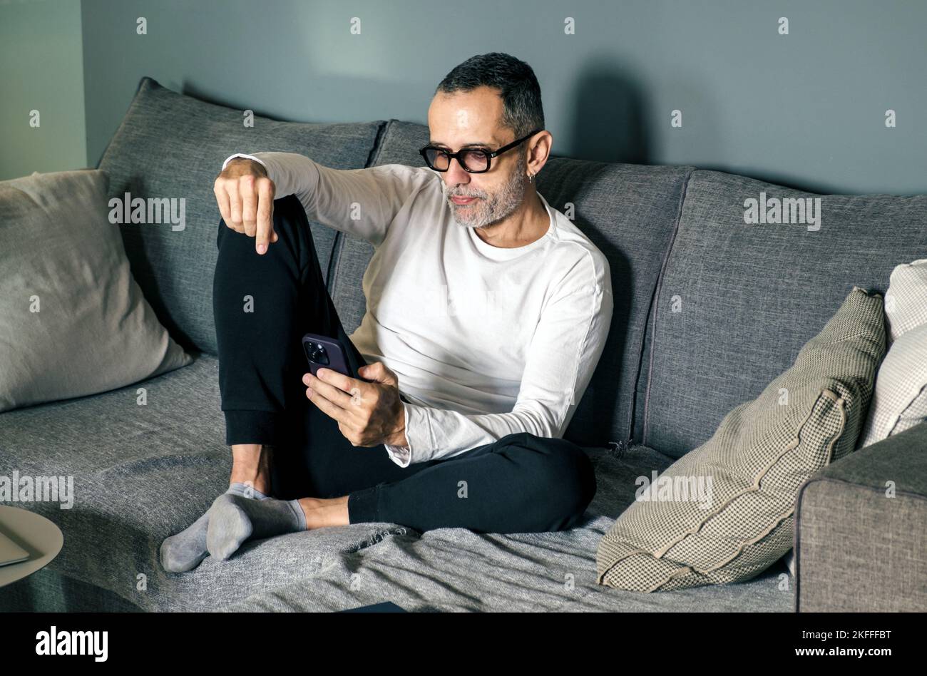 Man on couch with smartphone. Stock Photo