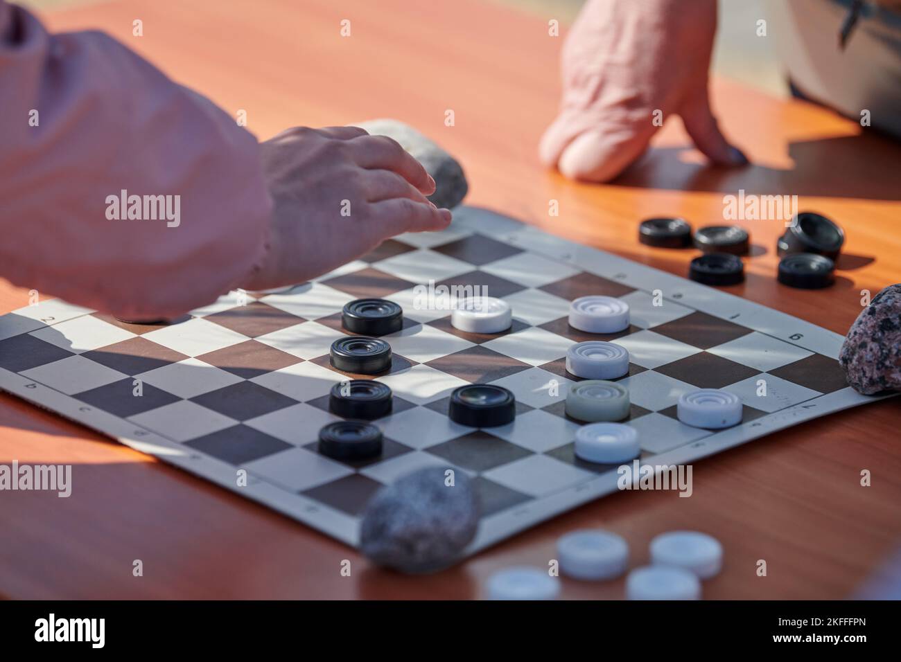 Outdoor draughts competition on paper checkerboard on table, close up