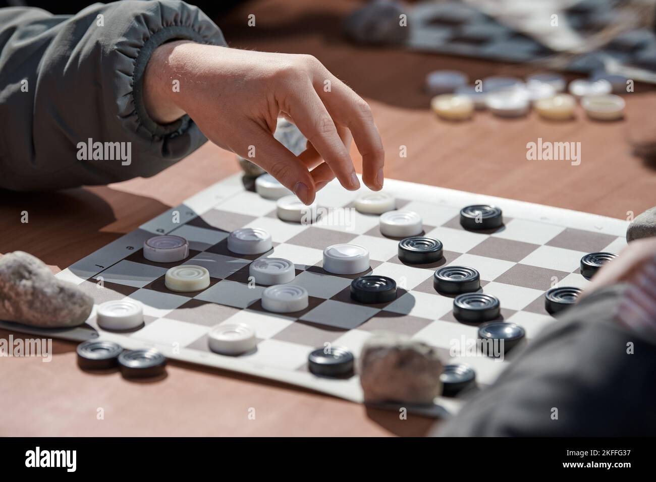 Outdoor checkers tournament on paper checkerboard on table, close up