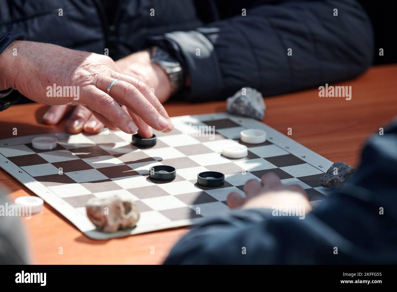 Outdoor draughts competition on paper checkerboard on table, close up