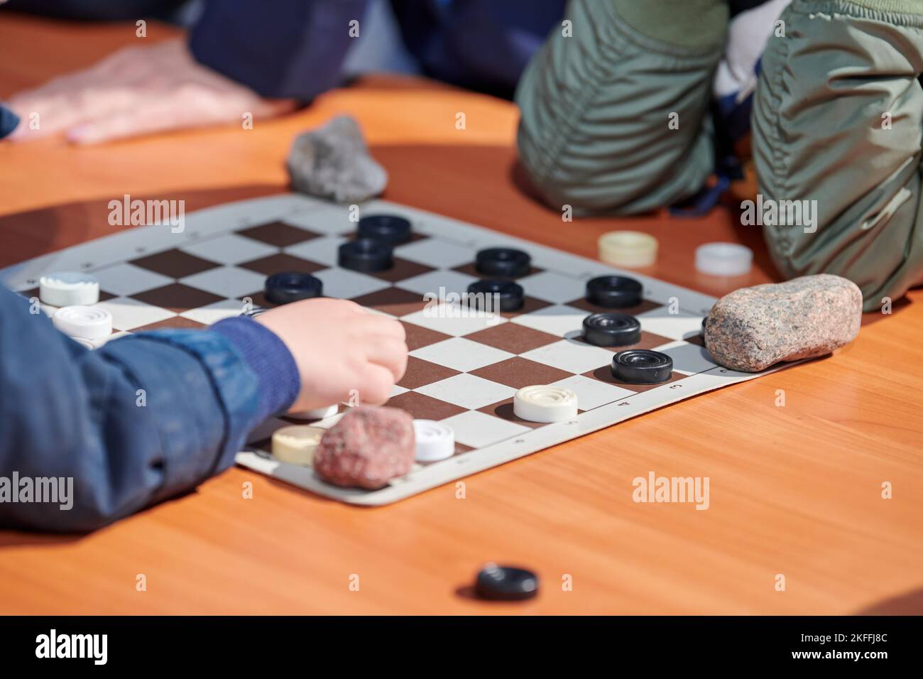Outdoor draughts competition on paper checkerboard on table, close up