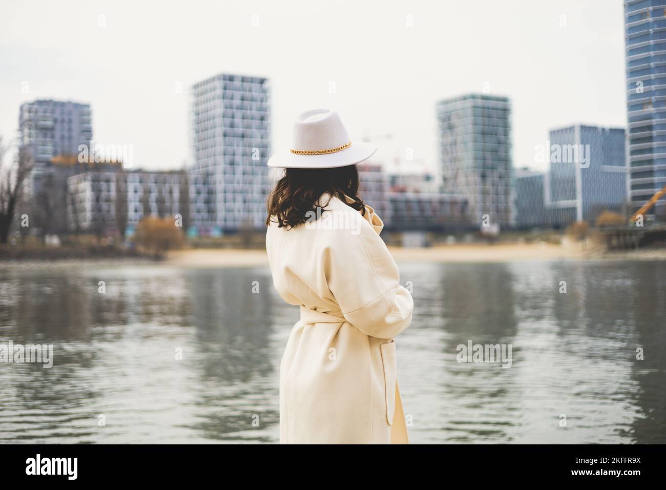 A woman with white hat from her back standing and watching a lake Stock ...